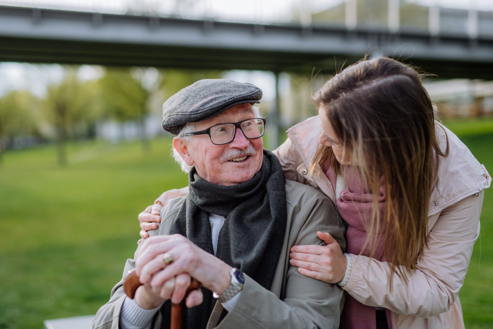 Happy senior with his adult daughter sitting outdoors in park.